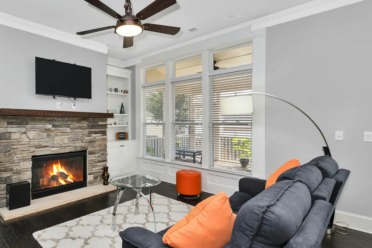 Living room with light gray walls, white crown molding, white built-ins and window trim, and a stone fireplace