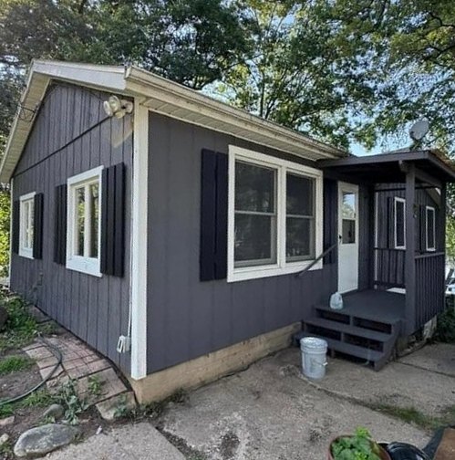 Cottage with charcoal siding, white trim and black shutters, after painting