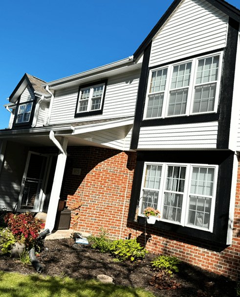 Two-story house with white lap siding, black window trim and a brick lower story