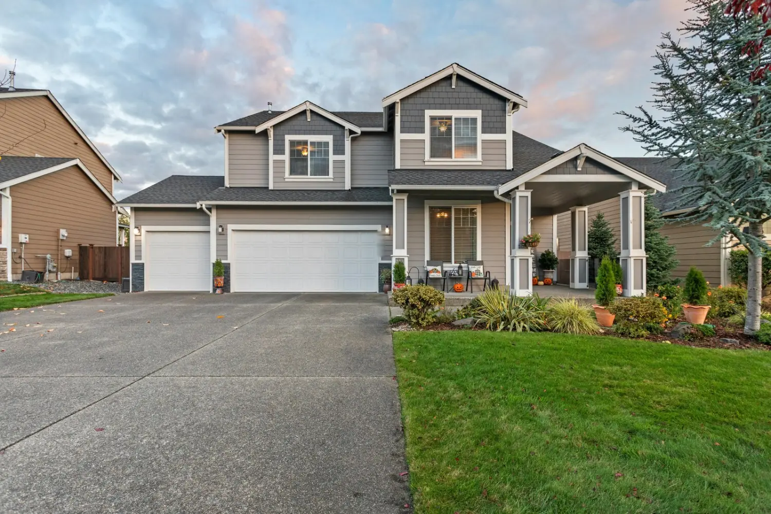 Two-story craftsman house with gray lap siding, shingle gables and white trim columns