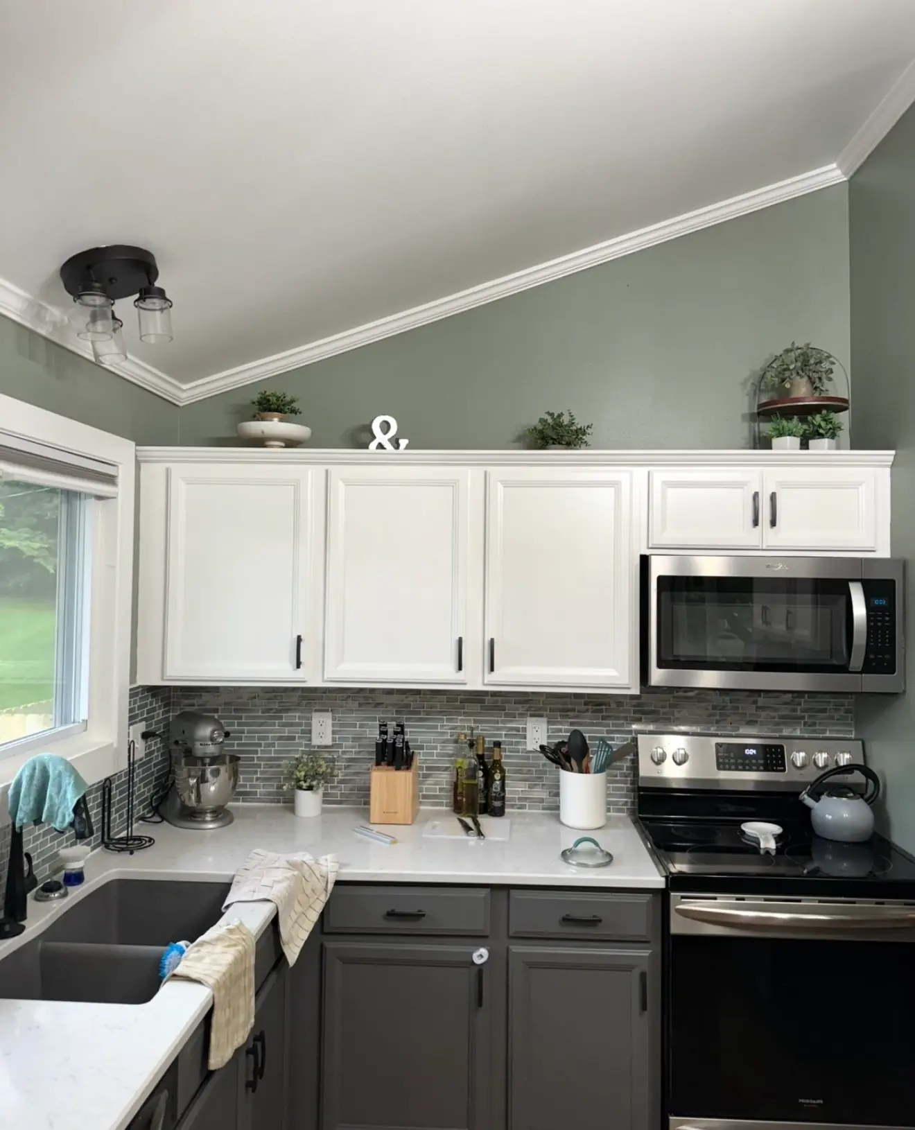 Kitchen with white upper cabinets, gray lower cabinets and sage-green walls